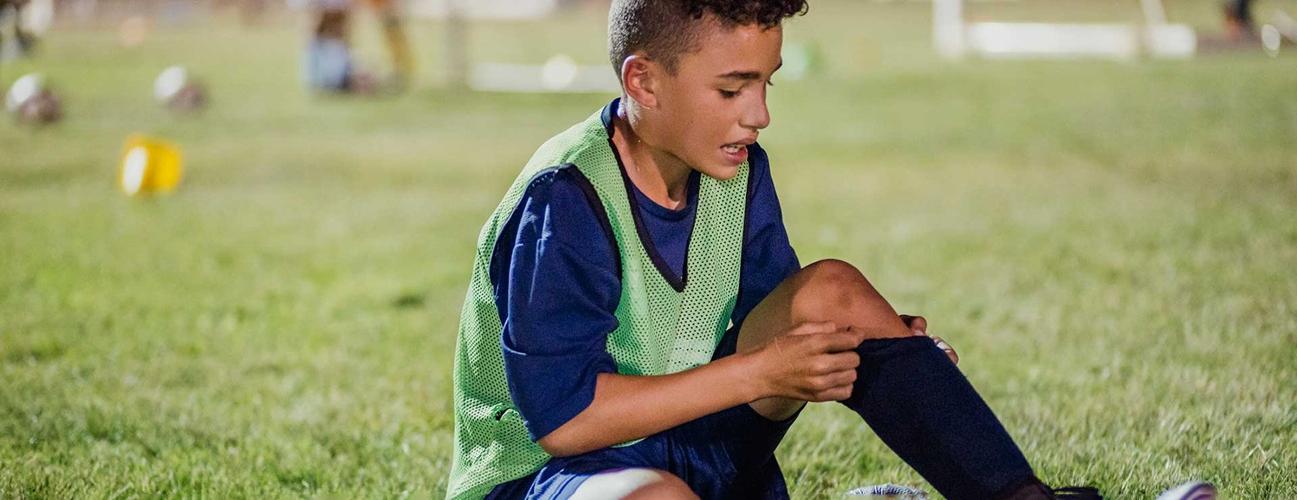 Young athlete on field with injured knee.